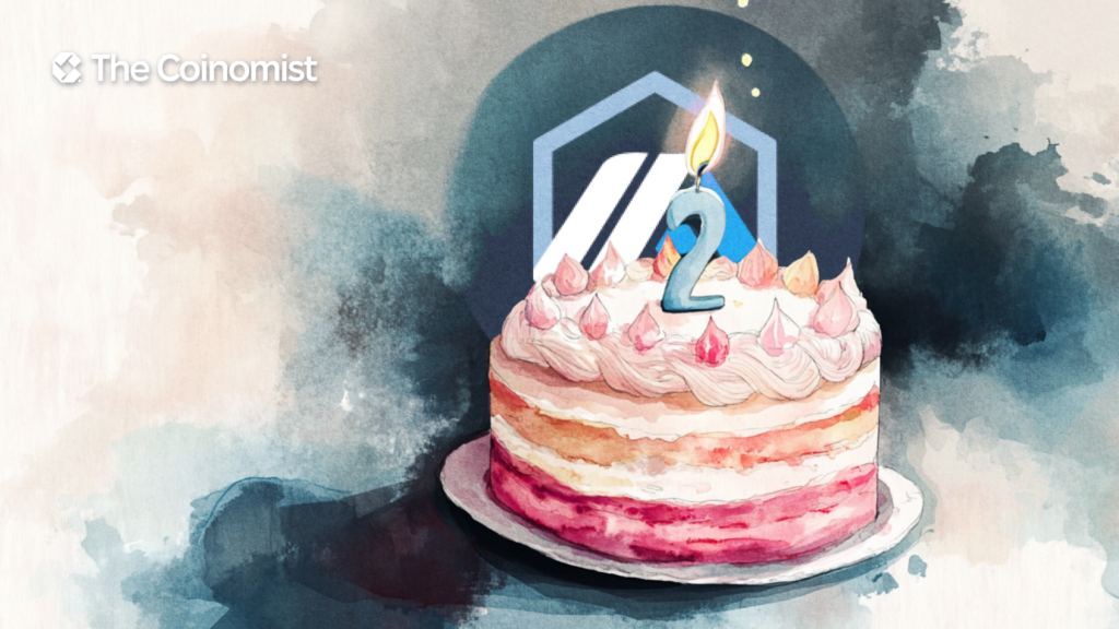 A cake with a '2' candle, with the Arbitrum logo in the background. - The Coinomist