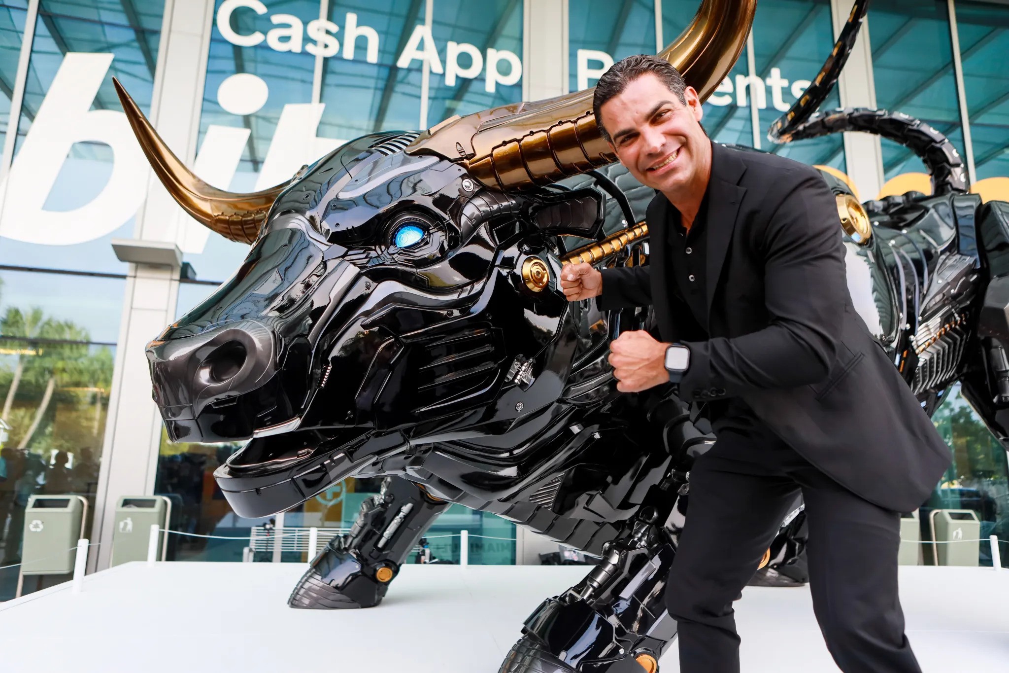 Francis Suarez standing next to the Miami Bull statue with glowing blue laser eyes, symbolizing the city's ambition to become a global crypto hub - The Coinomist
