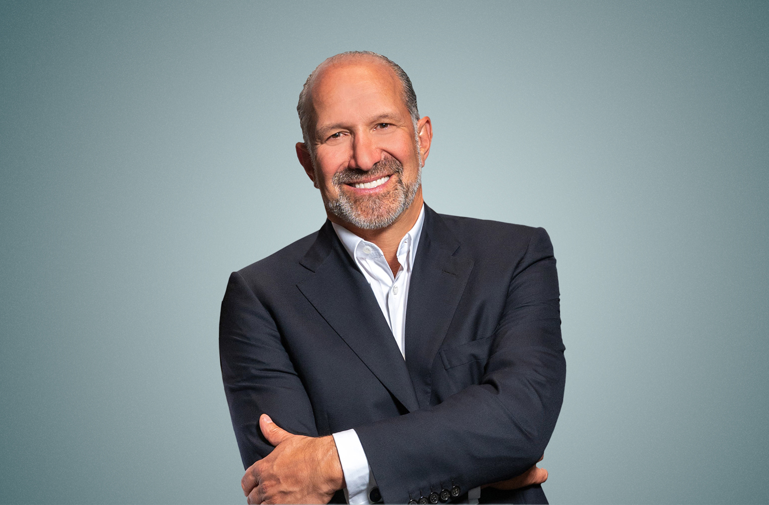 US Secretary of Commerce Howard Lutnick smiling in front of a gray background - The Coinomist