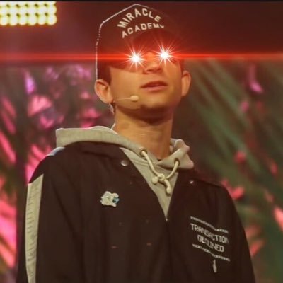 Jack Mallers on stage in a hoodie and cap, with digitally enhanced laser eyes—a meme-style nod to Bitcoin maximalism and crypto culture — The Coinomist