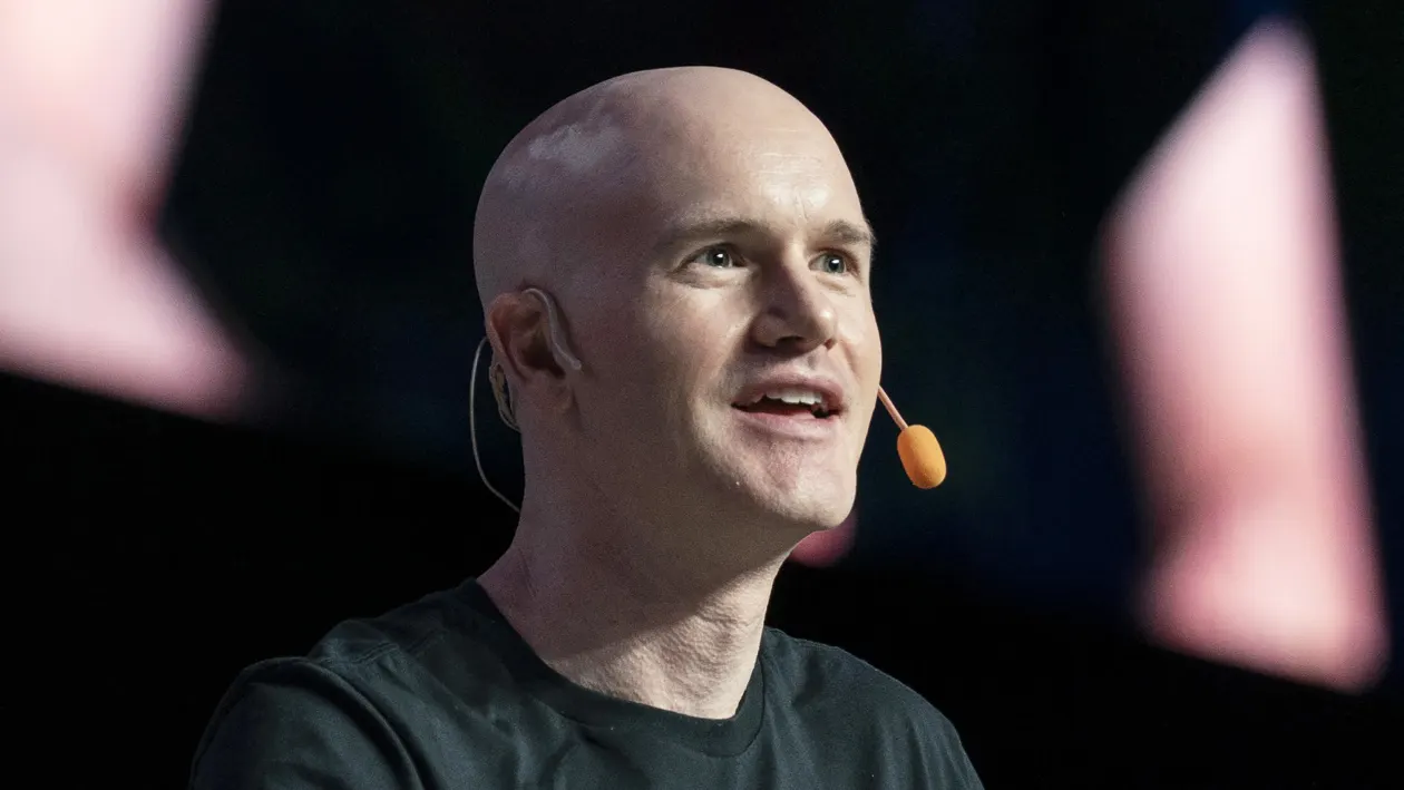 Brian Armstrong on stage in a black T-shirt, wearing a headset mic, speaking at the Singapore Fintech Festival — The Coinomist