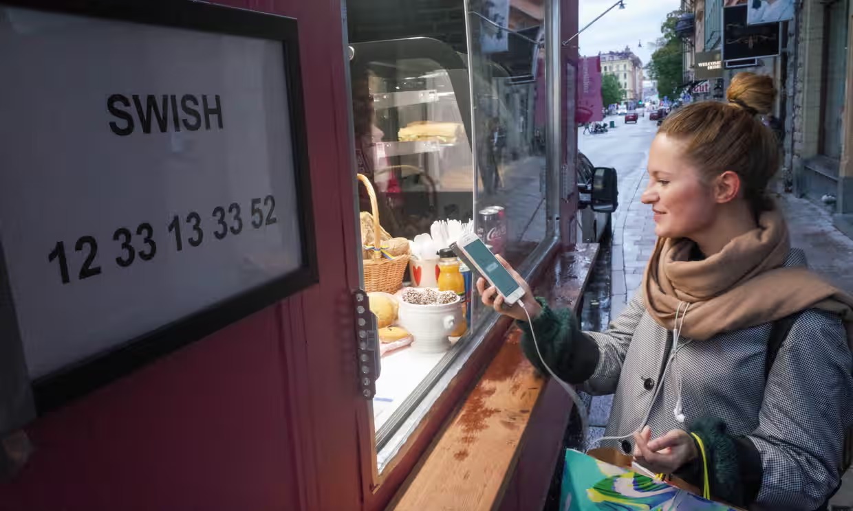 Woman in Stockholm paying with smartphone via Swish at a street vendor — The Coinomist