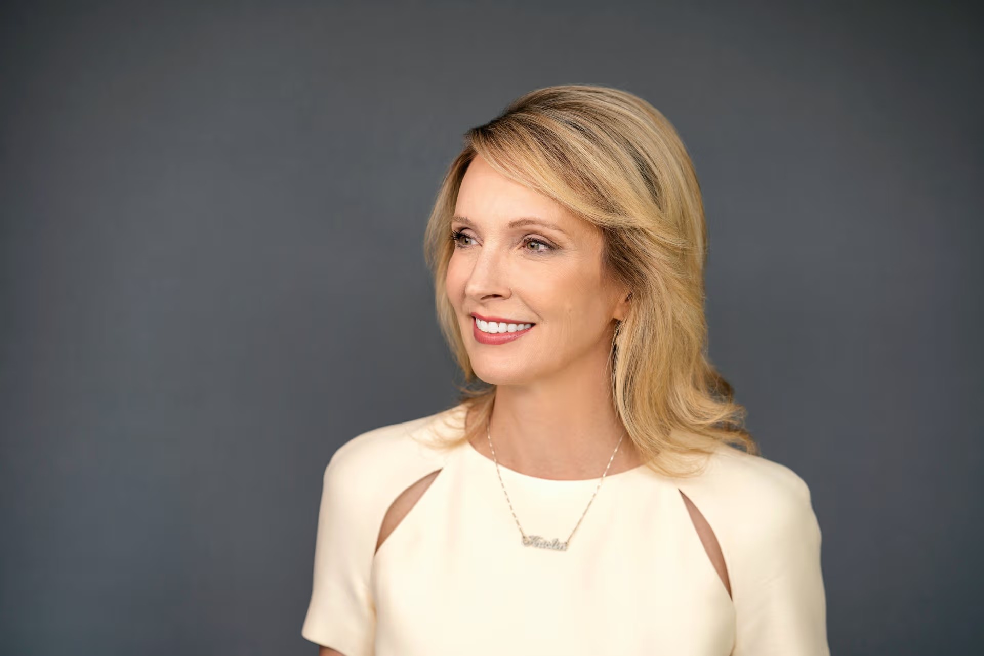 Kristin Smith in a cream blouse, smiling in front of a dark backdrop — The Coinomist