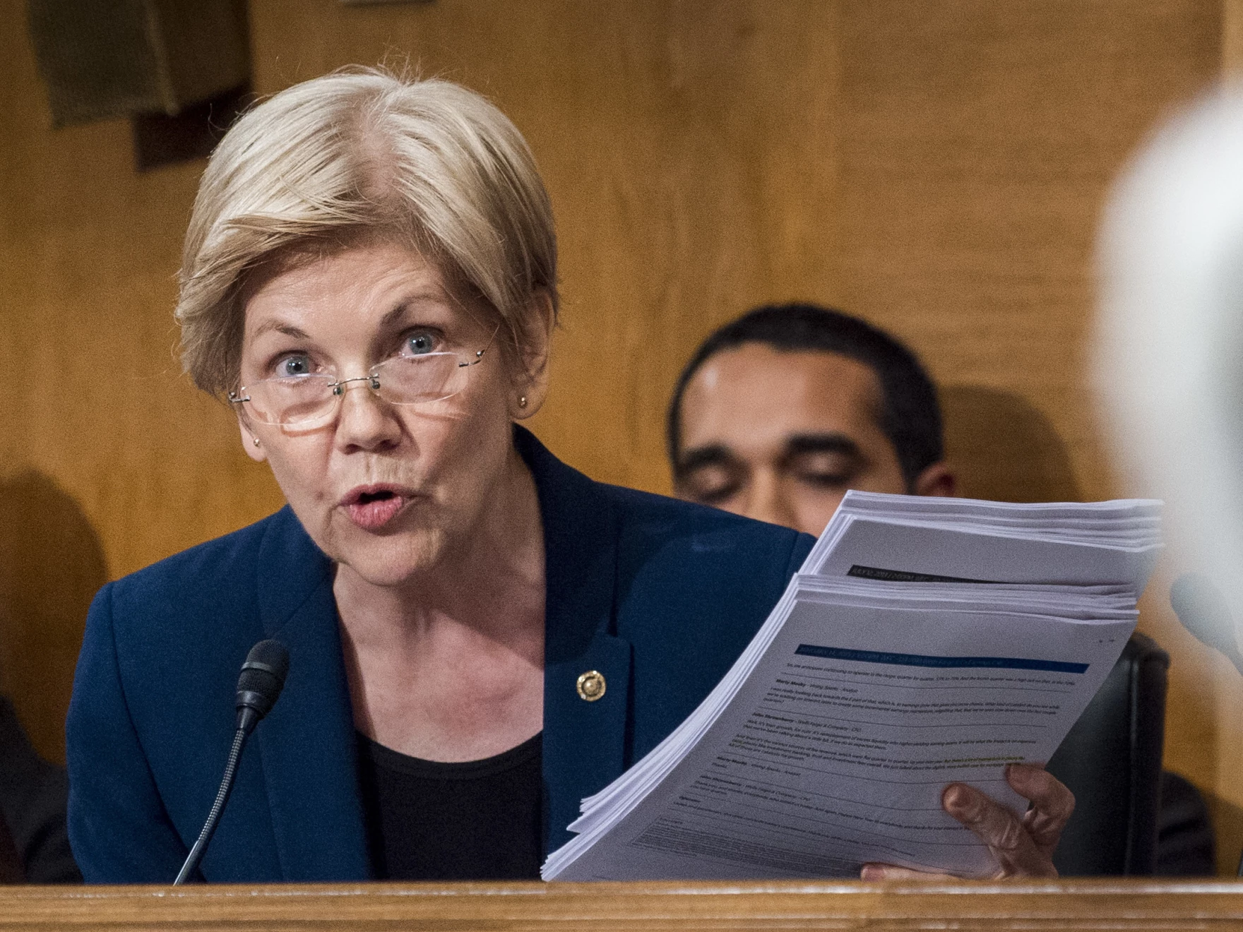 Elizabeth Warren holding printed documents, speaking into a microphone during a Senate hearing — The Coinomist