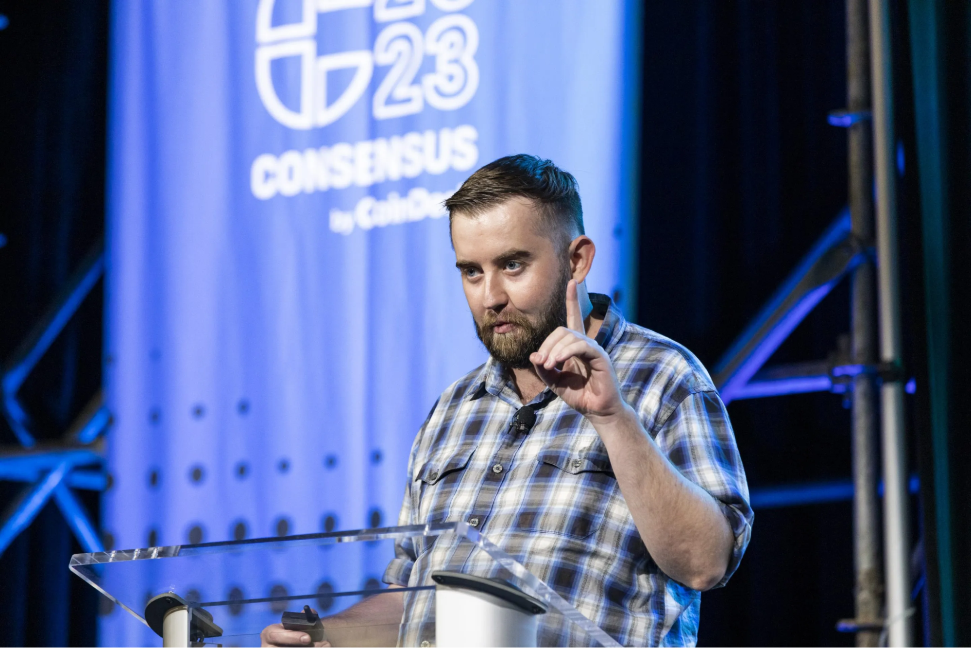 Sergey Nazarov speaking at Consensus 2023 in a plaid shirt. The Coinomist